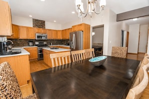 Una cocina moderna con armarios de madera, electrodomésticos de acero inoxidable y una mesa de comedor de madera oscura con sillas.