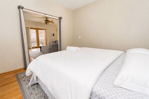 Ein Schlafzimmer mit einem großen Bett, einem Deckenventilator und Blick durch eine offene Tür.