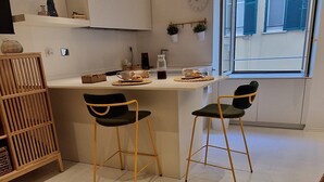 Una cocina moderna con comedor, que cuenta con un amplio ventanal, armarios blancos y dos sillas.