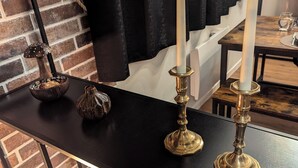 A room with a black table displaying candles, a decorative mushroom, and a bowl of snacks.
