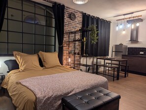Ein modernes Schlafzimmer mit einem großen Bett, einem kleinen Tisch und einer Küchenzeile in der Ecke.