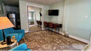 A living room with a blue sofa, a TV mounted on the wall, and a patterned carpet. - Pet & Large Boat OK 1 Bed Studio Near Marina & Beach Private Lot  Sleeps 2 (Fort Pierce)