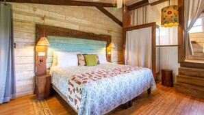 A rustic bedroom with a wooden ceiling, a bed with patterned bedding, two bedside lamps, and a window with curtains. - Villa Deluxe 9 rooms - 30 minutes from Tamarindo & 5 minutes from Playa Negra (Playa Negra)