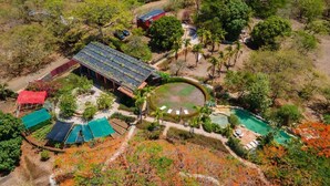 An aerial view of a resort with multiple buildings, a swimming pool, and surrounding vegetation. - Villa Deluxe 9 rooms - 30 minutes from Tamarindo & 5 minutes from Playa Negra (Playa Negra)