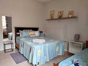 A bedroom with a bed, bedside table, nightstand, and a shelf with framed pictures. - Spacious 4-bedroom apartment in Praia with WiFi, for big size families. (Praia)