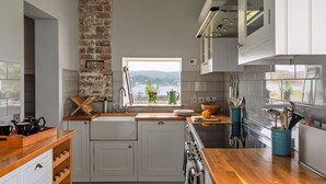 Een moderne keuken met witte kasten, een houten aanrecht en uitzicht op een meer door een raam.