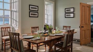 A dining room with a wooden table set for six, surrounded by chairs.