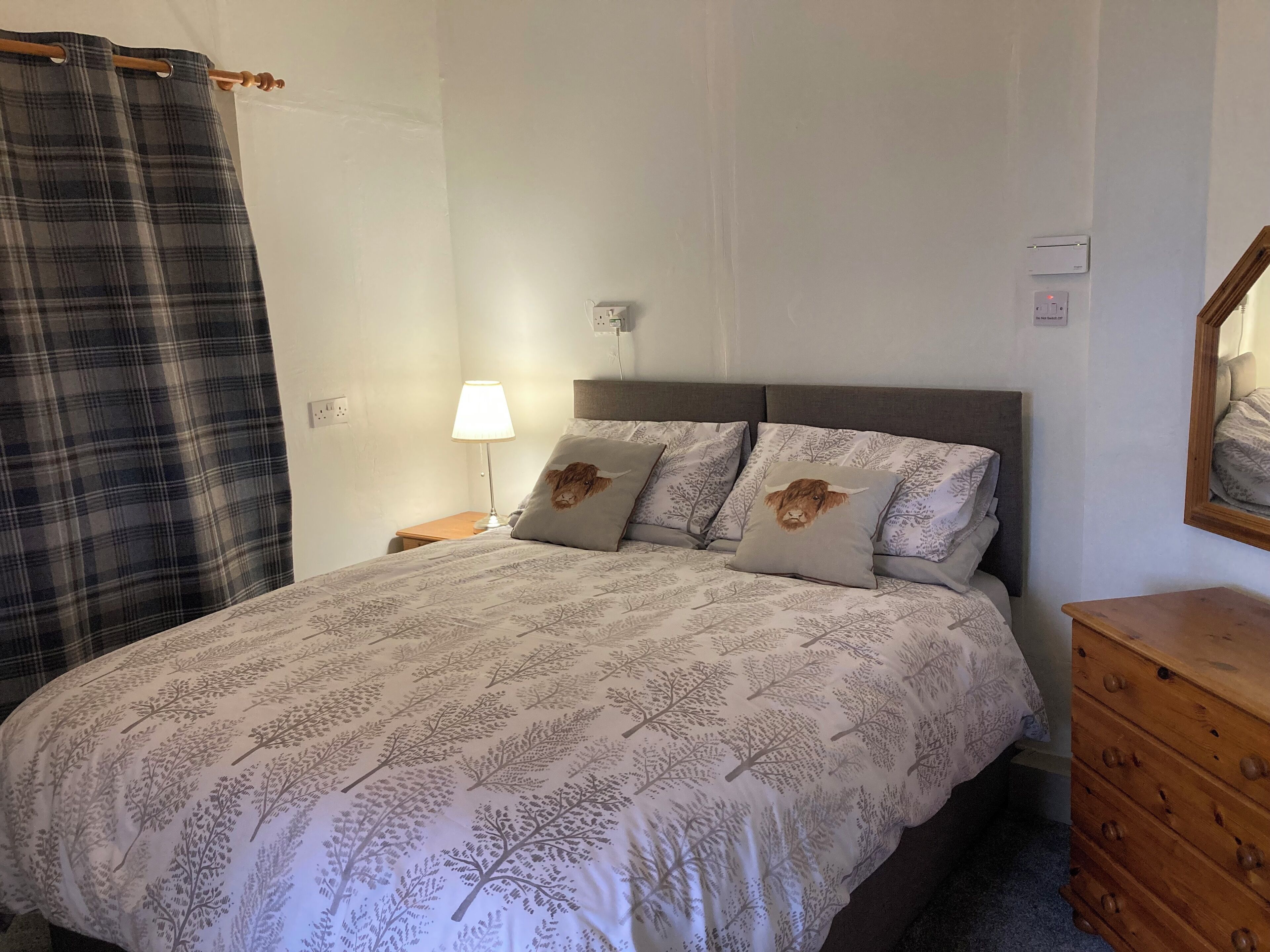 A bedroom with a bed, a nightstand, a lamp, a dresser, and a mirror.