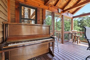 Un piano en bois sur une terrasse, avec un mur en pierre et une rambarde en bois.