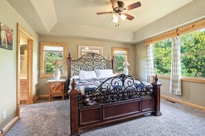 A bedroom with a large bed, a ceiling fan, and a view of the outdoors through a window. - The Cabin at The Land of the Yellow River (Necedah)