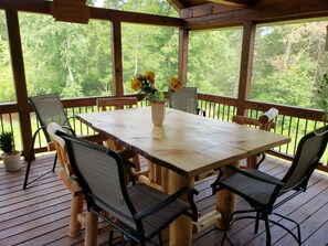 A wooden deck with a table and chairs, surrounded by a railing, overlooking a forested area. - The Cabin at The Land of the Yellow River (Necedah)