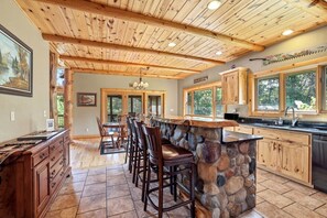 A spacious kitchen with a stone island, wooden ceiling, and large windows. - The Cabin at The Land of the Yellow River (Necedah)