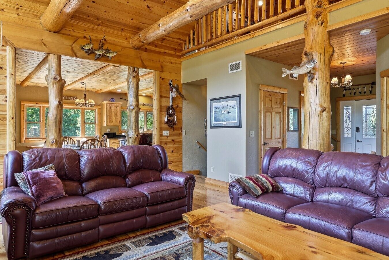 A cabin interior with two leather sofas, wooden flooring, and a dining area.