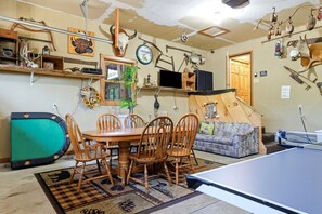 A room with a dining table, chairs, a ping pong table, and various hunting and fishing memorabilia on the walls. - The Cabin at The Land of the Yellow River (Necedah)