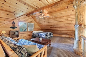 A cozy log cabin room with a loft bed, a sofa, a small table, and a ceiling fan. - The Cabin at The Land of the Yellow River (Necedah)