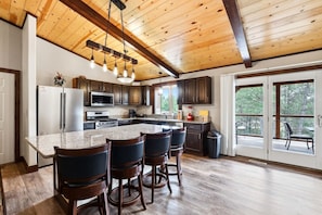 A kitchen with a granite countertop, stainless steel appliances, and a bar area with stools.