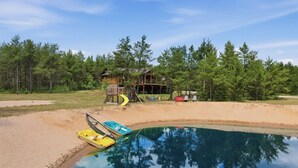 Ein Schwimmbad mit Booten, eine Holzterrasse und ein Haus, umgeben von Bäumen.
