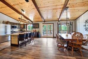 A spacious kitchen with a large island, bar stools, and a dining area with a wooden table and chairs.