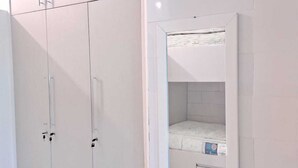 A bedroom with a white wardrobe, a bed, and a mirror on the wall. - Palladium Pousada (Neopolis)