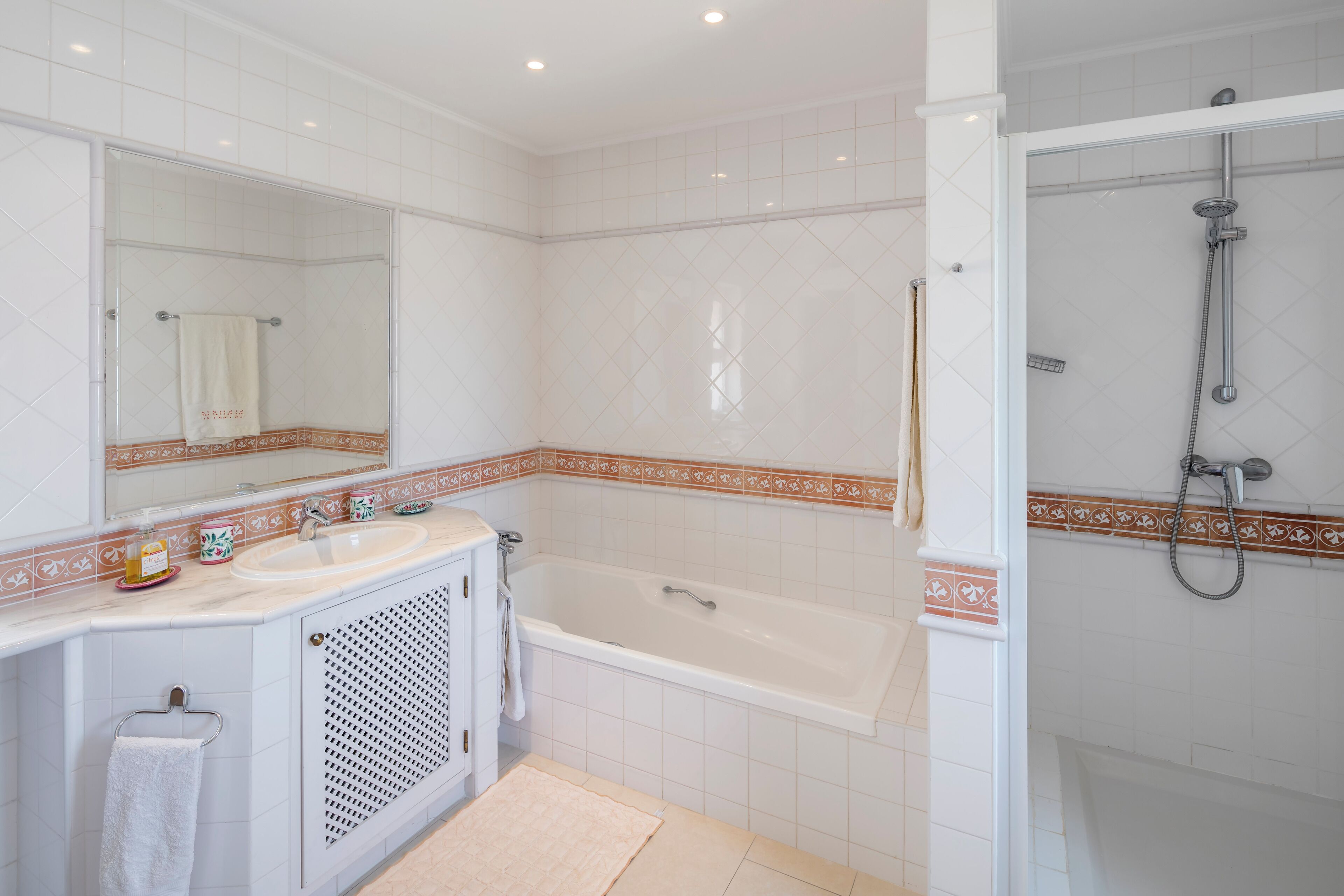 A bathroom with a bathtub, a shower, and a sink with a mirror above it.