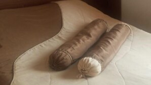 Un lit avec une tête de lit beige et marron, une petite table de chevet et un mur sobre.