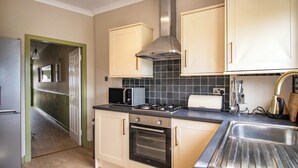 A compact kitchen with a built-in microwave, oven, and stainless steel sink.