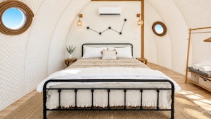 A cozy, tent-like bedroom with a bed, bedside tables, and a circular window.
