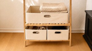 A wooden wardrobe with multiple shelves and hanging space, featuring a quilted wall in the background.