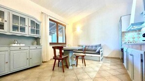 Eine kleine Küche mit Esstisch und Stühlen, einer Couch und Schränken.