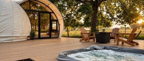 A hot tub, wooden deck, outdoor seating, and a tent-like structure.