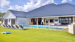 Ein modernes Haus mit Swimmingpool, überdachter Terrasse und gepflegtem Rasen.