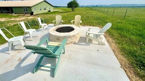 Ein Außenbereich mit Sitzgelegenheiten, einem Feuerkorb, Stühlen und einem Picknicktisch.