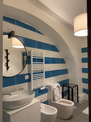 Experience the unique architectural charm of this bathroom, featuring a curved archway and striking blue and white striped tiles.