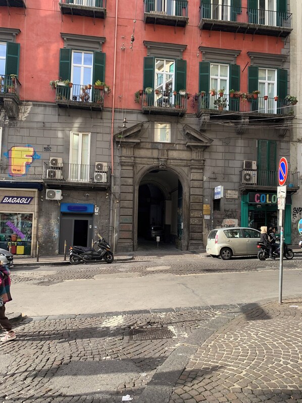 Classic building with arched entrance, greenery, and storefront.