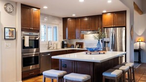 A modern kitchen with stainless steel appliances, wooden cabinets, and a large island with bar stools.