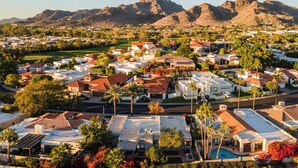 A residential area with houses, a swimming pool, and mountains in the background.