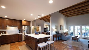A spacious kitchen with a large island, wooden cabinets, and a tiled floor.