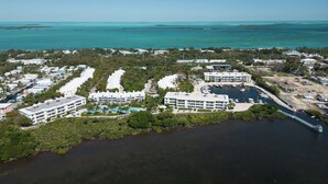 An aerial view of a coastal resort with multiple buildings, a marina, and a large body of water.