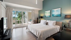 A bedroom with a large bed, a TV, and a balcony with curtains.
