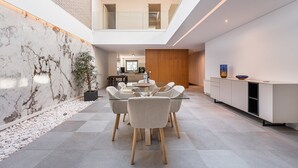Ein modernes Interieur mit Essbereich, Küche und einer hohen Decke mit Oberlichtern.