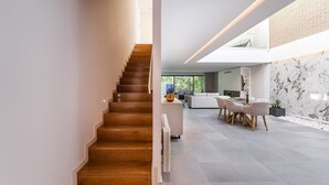 Ein modernes Interieur mit einer Holztreppe, die in einen Wohnbereich mit Esstisch und Stühlen führt.