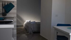 A compact hotel room with a bed, a small table, and a chair. - Vesuvio Home Capodichino Blue (Naples)