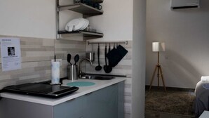 A modern kitchen with a built-in stove, a sink, and a coffee machine. There is a sign on the wall and a lamp in the corner. - Vesuvio Home Capodichino Blue (Naples)