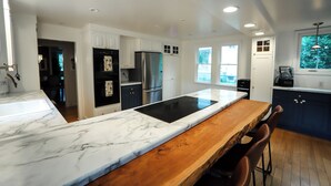 Een moderne keuken met witte kasten, een houten eiland en roestvrijstalen apparatuur.