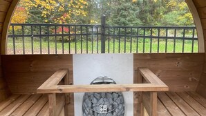 A wooden structure with a semi-circular arch window overlooking a garden with yellow foliage. - Family-Friendly Historic Home with Private Sauna and Spacious Yard (Homer)