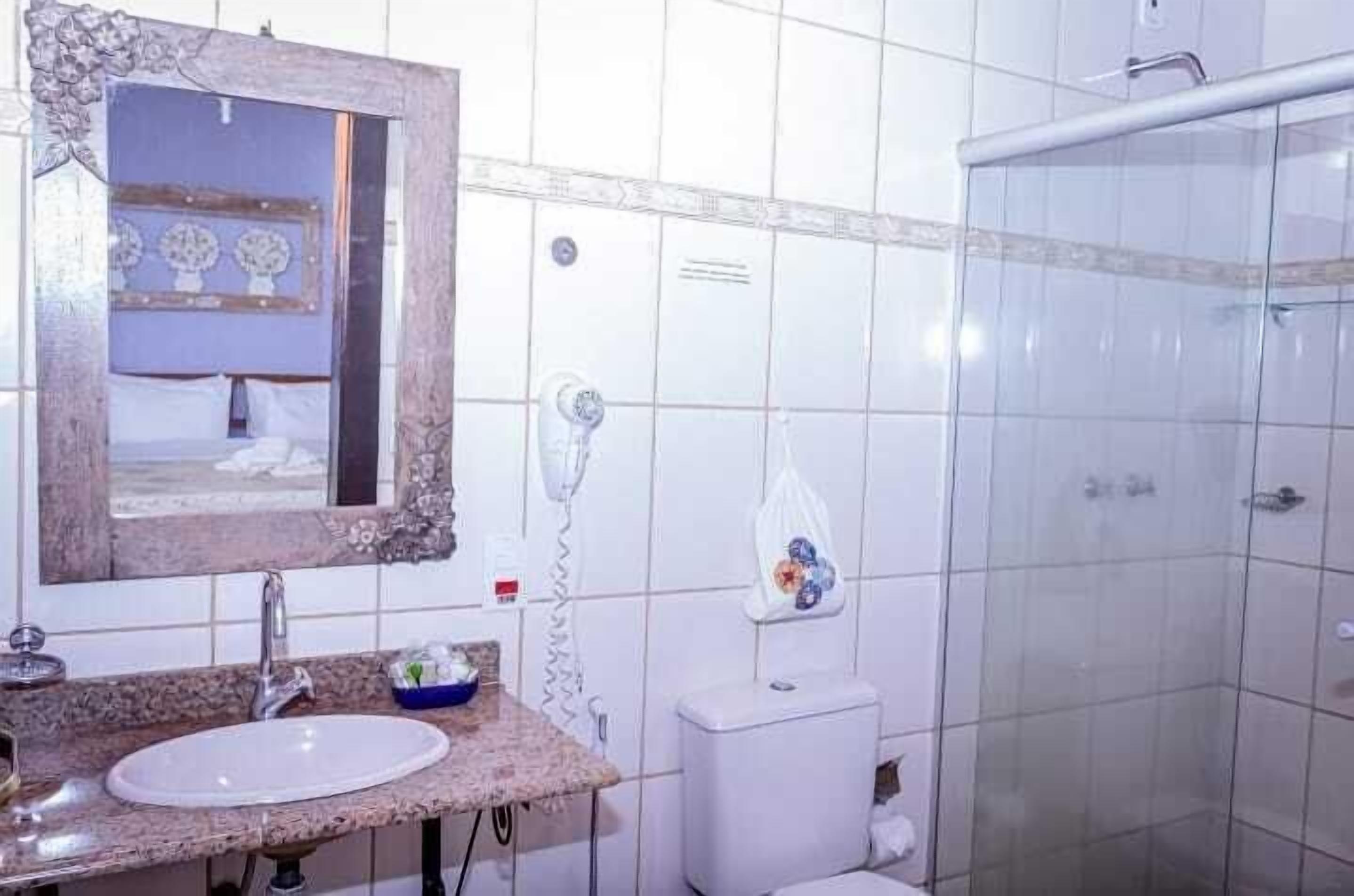 A bathroom with a sink, mirror, toilet, and shower.