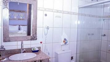 A bathroom with a sink, mirror, toilet, and shower.