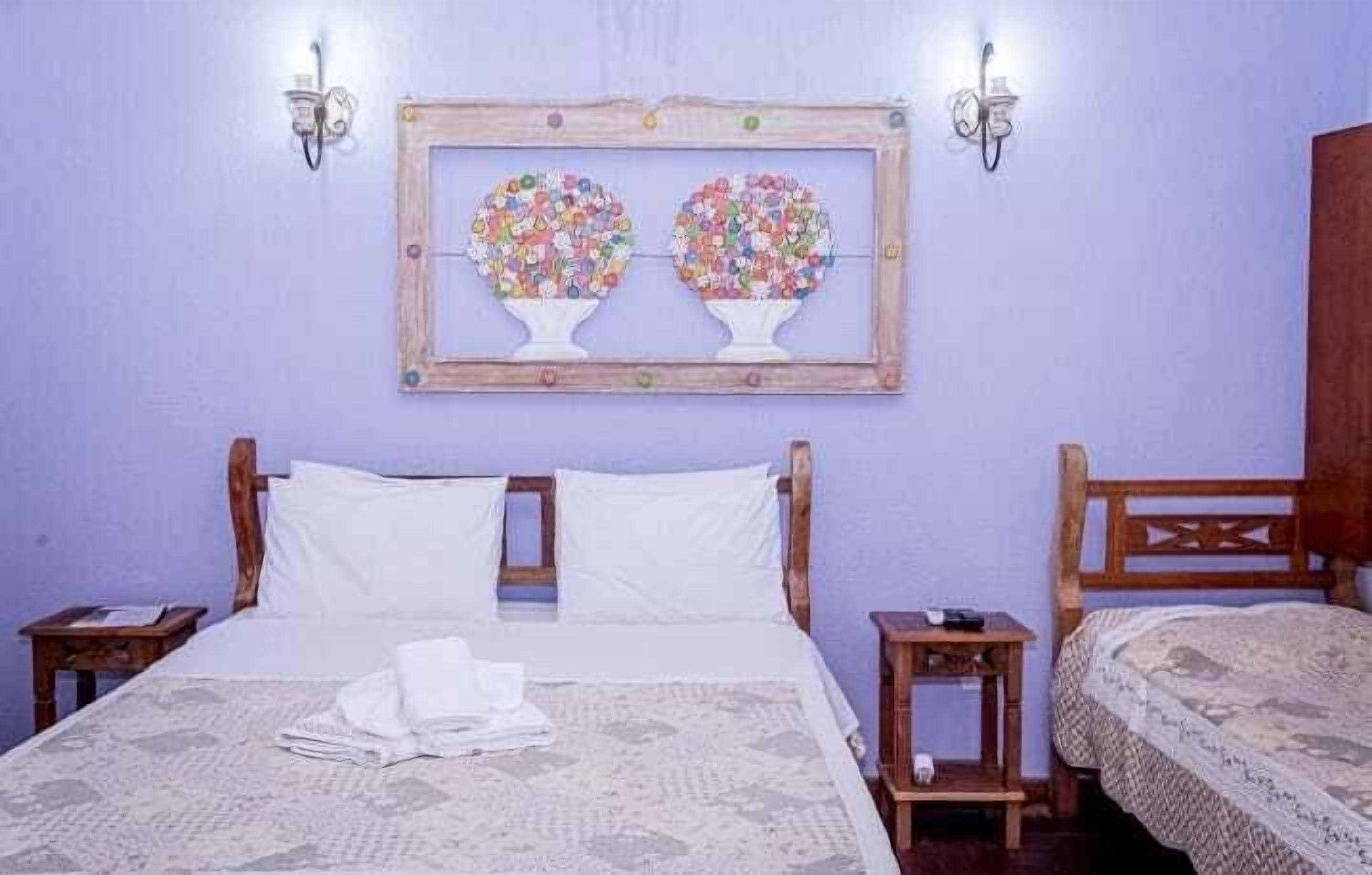 Un dormitorio con cama, dos mesitas de noche, cabecero de madera y un cuadro colgado en la pared.