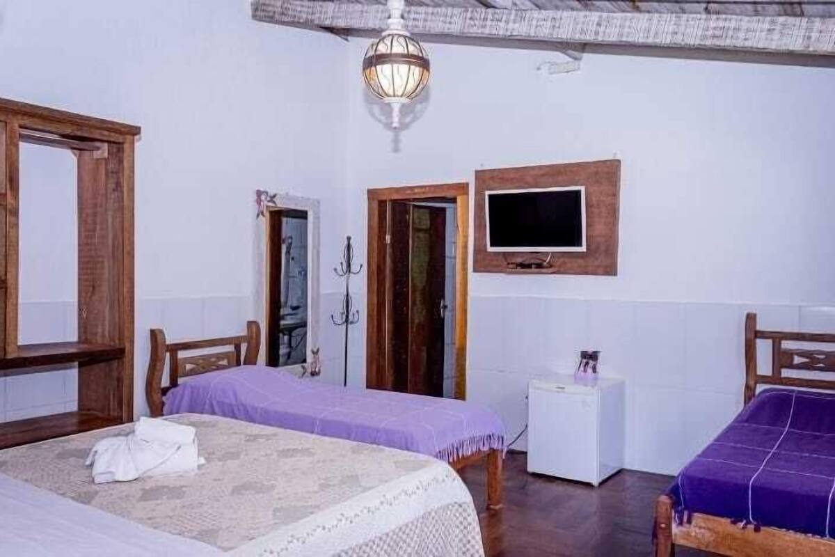 A room with two beds, a television, a small white table, and a hanging light fixture.