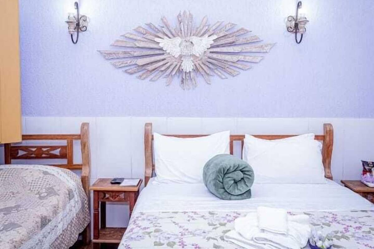 A hotel room with a bed, a nightstand, and a wall decoration.